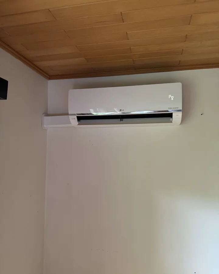LG airco binnenunit onder een houten plafond in de slaapkamer
