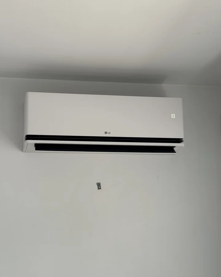 LG binnenunit hoog tegen een witte wand in de eerste kamer
