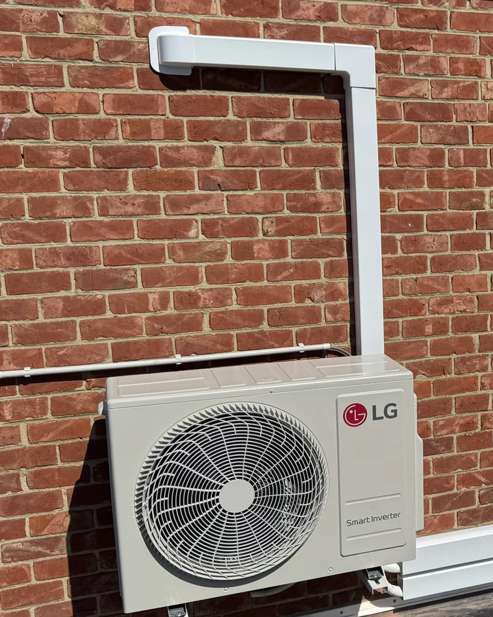 LG buitenunit op wandbeugels boven het platte dak, met de leidingkoker netjes langs de gevel omhoog