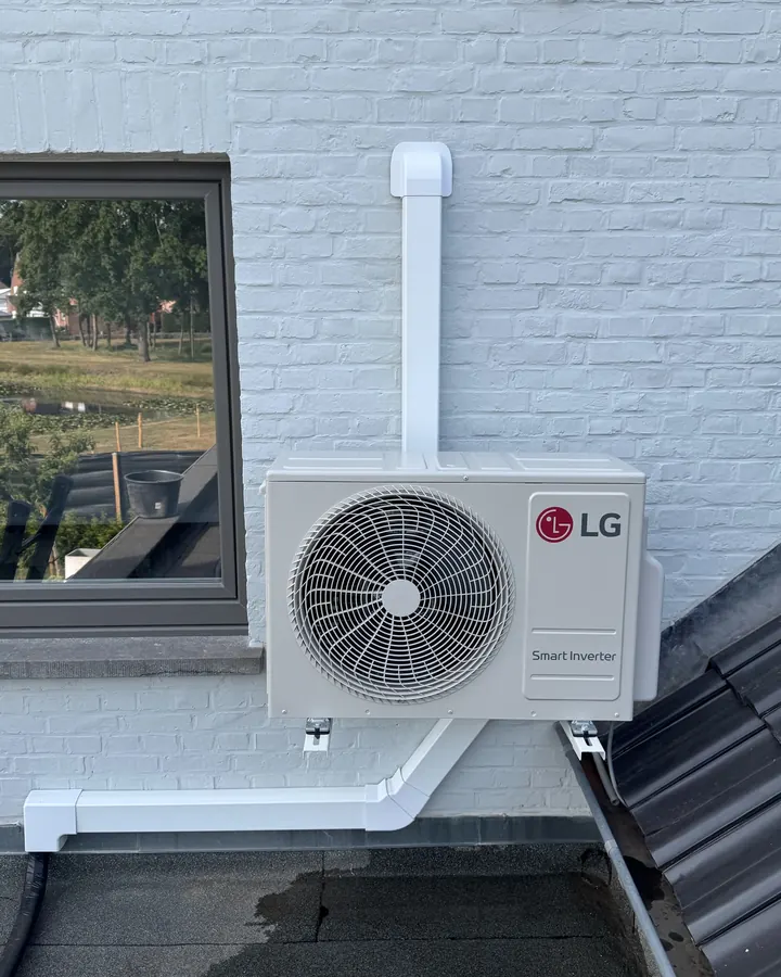 LG airco buitenunit op wandbeugel naast een dakraam