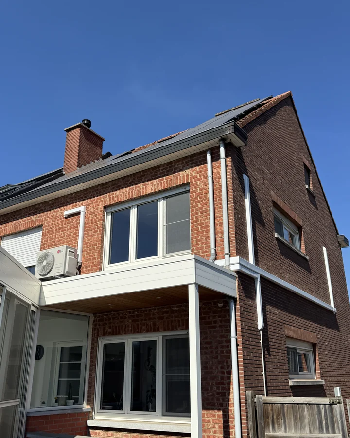 De woning vanaf de tuinzijde, met de buitenunit op het dak van de veranda
