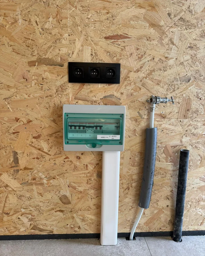 Het afgewerkte bord met etiket, met daarboven drie stopcontacten in Niko Intense Black