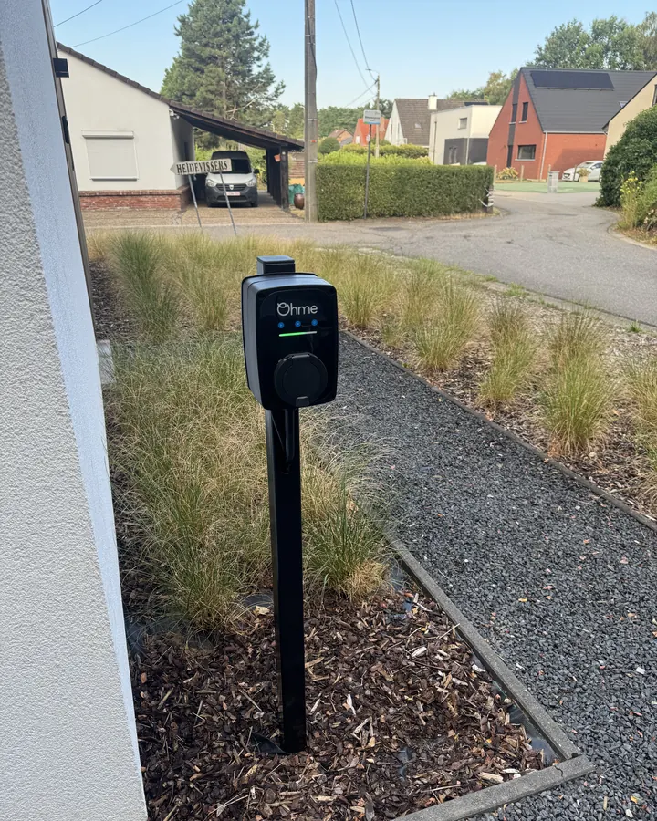 Het afgewerkte laadpunt: de beplanting ligt terug rond de paal en het laadpunt is klaar voor gebruik