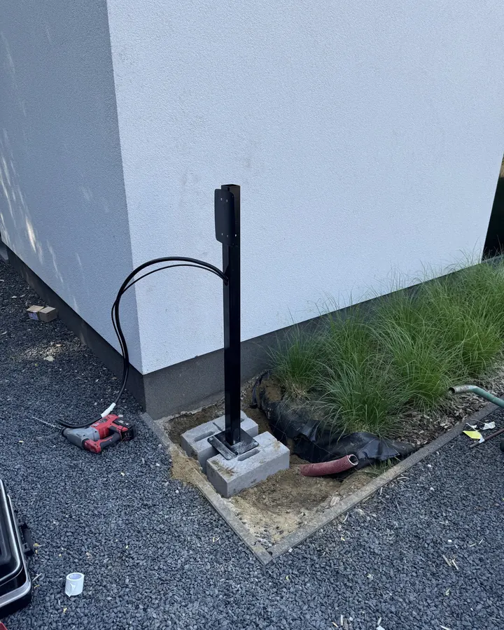 De laadpaal staat op zijn betonnen voet, kabel aangesloten